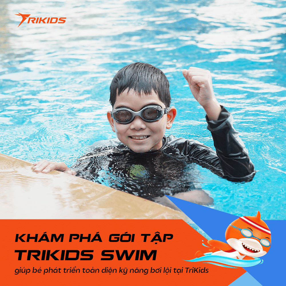Học viên TriKids đeo kính bơi mỉm cười bên thành hồ bơi